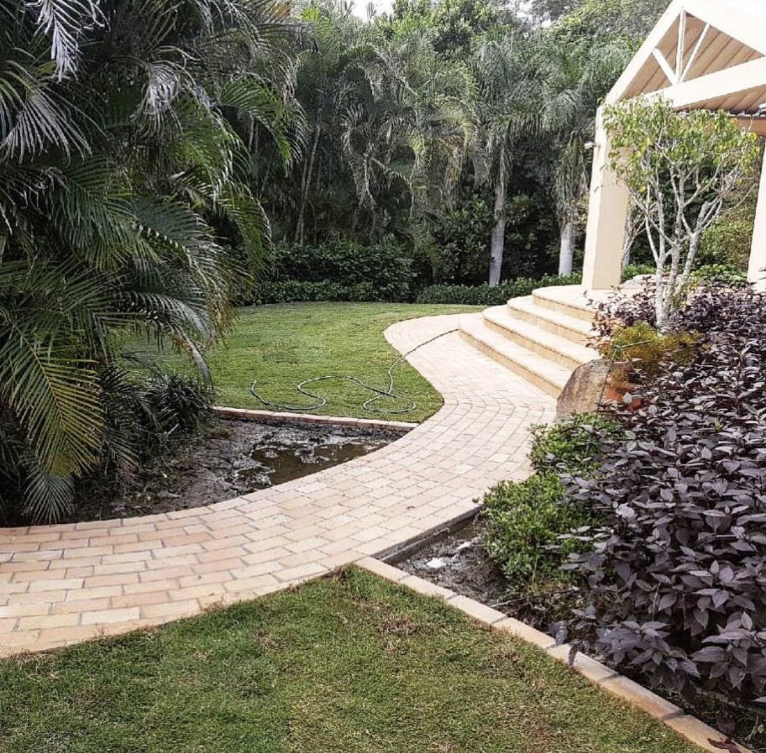 Curved brick-paved path through lawn and garden beds